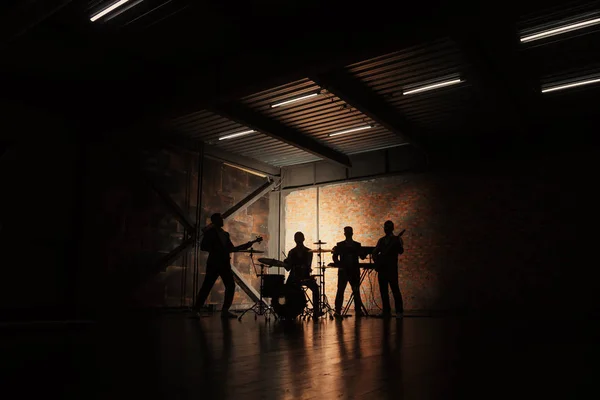 Musique et mode. Beaux jeunes hommes en costumes jouant du rock et chantant des chansons. Bandes silhouettes avec sur un concert . — Photo