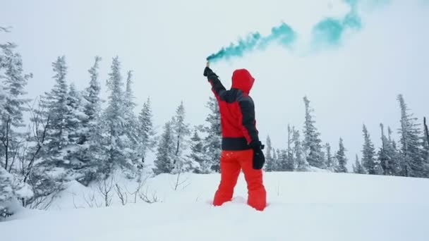 Молодой человек играет с дымовыми шашками на вершине гор в зимнем лесу — стоковое видео