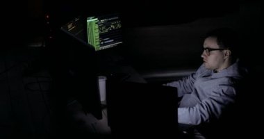 Haritalar ve veriler üzerinde göstermek perde bir karanlık office odada bulunan bir bilgisayarda bir Hood erkek hacker çalışır
