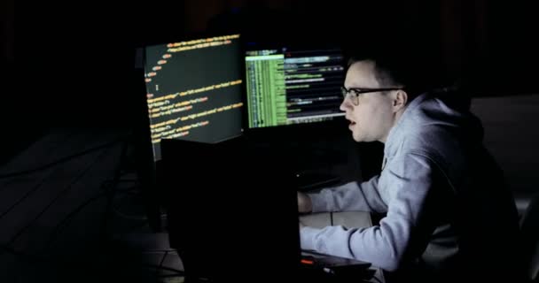 Un hacker maschio che lavora su un computer. hacker in occhiali sta lavorando sul computer nel centro di sicurezza informatica pieno di schermi di visualizzazione . — Video Stock