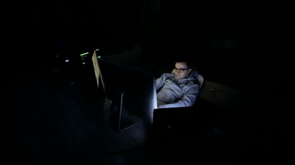 Männliche Hacker an einem Computer arbeiten. Hacker mit Brille arbeitet an Computer in Cyber-Sicherheitszentrum voller Displays. — Stockvideo