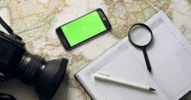 Üstten Görünüm. Yeşil ekranlı akıllı telefon günlüğü üzerinde yatıyor. Tatil Planlama. Chroma anahtar