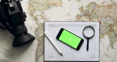 Üstten Görünüm. Yeşil ekranlı akıllı telefon günlüğü üzerinde yatıyor. Tatil Planlama. Chroma anahtar