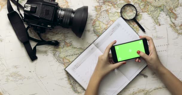 Vista superior. mujer viajero manos utilizando el teléfono inteligente con pantalla verde. manos flojas desplazándose, tocando en la pantalla táctil. Planeando vacaciones. Clave de croma — Vídeos de Stock