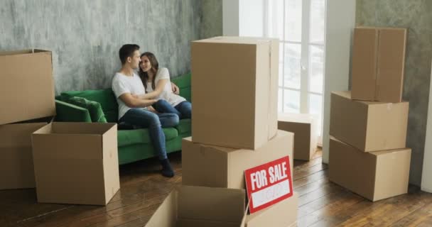 Mladý pár, relaxační, směje se po rozbalení krabičky od domu přesunout — Stock video