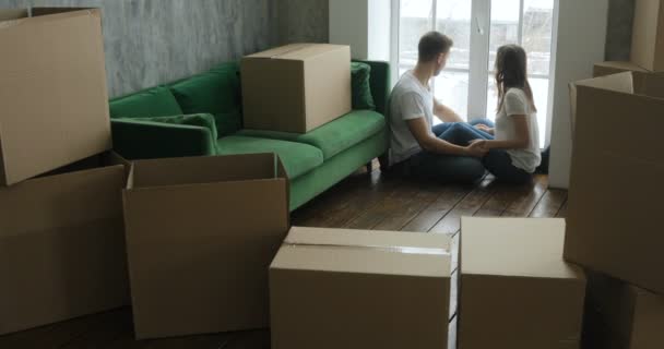 Jong koppel ontspannen lachen na het uitpakken van de kartons van huis verplaatsen — Stockvideo
