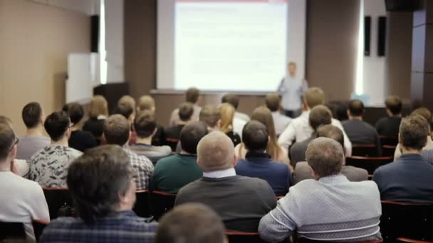 Lidé na konference nebo prezentace, dílny, mistrovskou třídu fotografii. Přednášející říká a ukazuje prezentace na obrazovce Projektivní. Pohled zezadu — Stock video