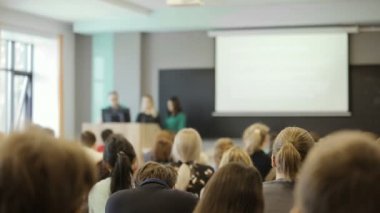 Grup oditoryum masalarında oturup ve bir ders öğretmenleri tutar olarak dinleme Üniversitesi Öğrenci.