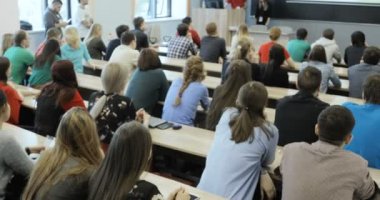 Grup oditoryum masalarında oturup ve bir ders öğretmenleri tutar olarak dinleme Üniversitesi Öğrenci.