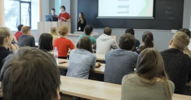 Veja por trás de um grupo de alunos em uma sala de aula, ouvindo como seu professor realiza uma palestra. vista para trás — Vídeo de Stock