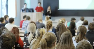Grup oditoryum masalarında oturup ve bir ders öğretmenleri tutar olarak dinleme Üniversitesi Öğrenci.