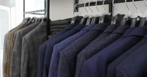 La fila di uomini va bene a giacche su grucce. Raccolta di nuovi bei vestiti appesi a appendini in un negozio — Video Stock
