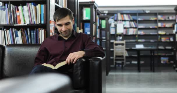 Студент читає книжку в бібліотеці. Концепція: освітній, портрет, бібліотека, розсудливий, розслаблений . — стокове відео