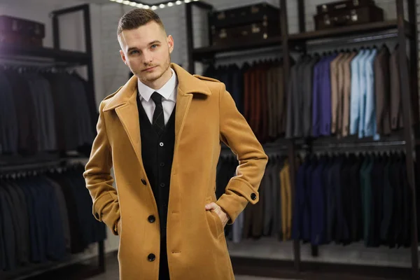 Handsome man stands in suit shop fashionable rich male dressed in expensive clothes posing indoors — Stock Photo, Image