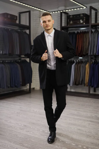 ポーズを屋内で高価な服に身を包んだファッショナブルな豊かな男性のスーツ ショップにハンサムな男が立っています。 — ストック写真
