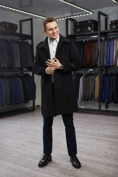 Молодой красивый мужчина в пальто в магазине костюмов — стоковое фото