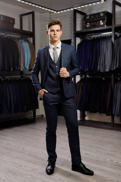 Verkoop, winkelen, mode, stijl en mensen concept - elegante jongeman kiezen en proberen jas op in mall of kledingwinkel — Stockfoto