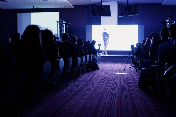 Sahnede, iş ve eğitim yatırım kavramı hakkında hoparlörlere sahip konferans salonu veya seminer toplantı seyirci görünümünde arka