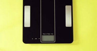 Kadın ağırlığını tartıya veriyor, ağırlığı 56.3 kg, ayakları yakın çekim..