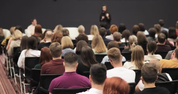 Affärsforum med kvinnlig talare som talar i stor publik, vy från tittare. — Stockvideo