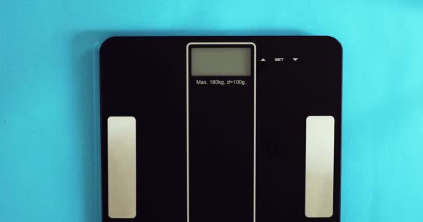 Жінка важить стоячи на вагах, вага на дисплеї 56,3 кг, крупним планом . — стокове відео