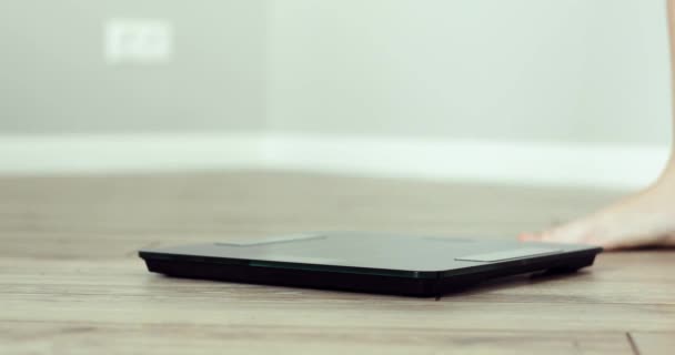 Barefooted woman is standing on scales weightning at home in room, feet closeup. — Stock Video