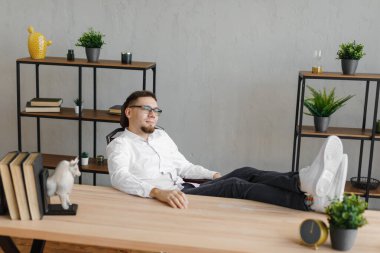 Genç bir adamın masada oturup, gözlerini kaçırıp düşünmesi..