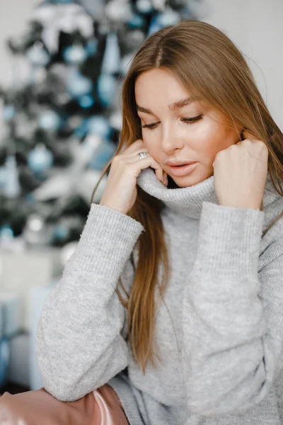 Διακοπές, γιορτή και άνθρωποι έννοια - νεαρή γυναίκα σε κομψό σε ένα πουλόβερ πάνω από τα Χριστούγεννα εσωτερικό φόντο — Φωτογραφία Αρχείου