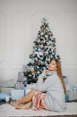 Tatiller, kutlamalar ve insanlar konsepti - Noel arkaplanı boyunca süveter giyen zarif genç kadın