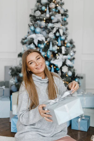 Vacaciones, celebración y concepto de la gente - mujer joven en elegante en un suéter sobre fondo interior de Navidad — Foto de Stock