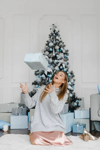 Feliz joven mujer vomita regalos cerca del árbol de Navidad — Foto de Stock