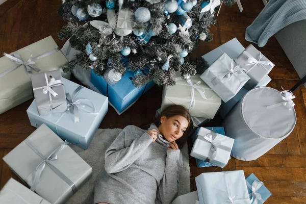 Chica se encuentra en el suelo, rodeado de regalos, cerca del árbol de Año Nuevo, vista superior, concepto de Año Nuevo — Foto de Stock