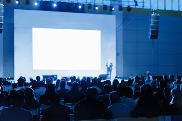 El público escucha el discurso del profesor en la sala de conferencias. foto teñida de azul Enfoque en personas irreconocibles — Foto de Stock