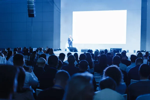 O público ouve o palestrante na sala de conferências. foto matizado azul Imagem De Stock