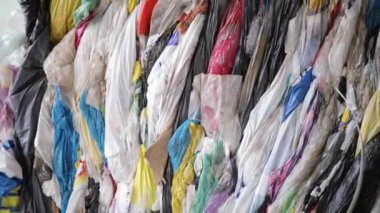 Geri dönüşüm fabrikasında sıralanmış plastik paketler ve çantalar, hareket halinde yakın çekim görüntüsü.