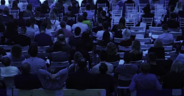 Зрители в аудитории сидят на стульях и смотрят в камеру. . — стоковое видео