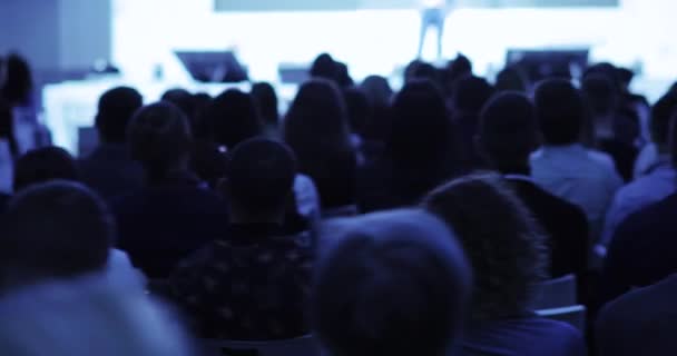 Kijkers luisteren spreker en lookin presentatie op conferentie, backview. — Stockvideo