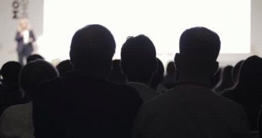İzleyiciler, kadın konuşmacı ve konferansta sunumu dinliyorlar..