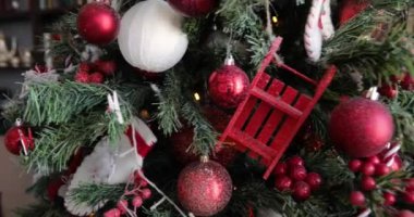 Dallarda kırmızı toplar, böğürtlenler, çelenkler ile süslenmiş dönen Noel ağacı.