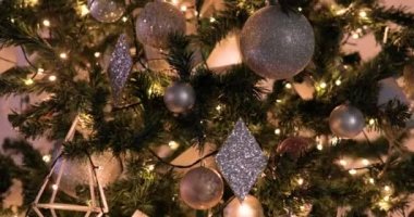 Altın toplar ve çelenklerle süslenmiş Noel ağacı etrafında dönüyor.