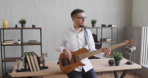 Giovane uomo sta giocando alla chitarra in ufficio durante la pausa con gli auricolari nelle orecchie . — Video Stock