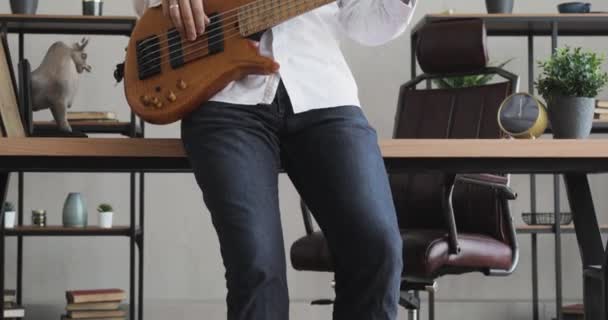 Homem está tocando na guitarra no escritório durante a pausa com fones de ouvido . — Vídeo de Stock