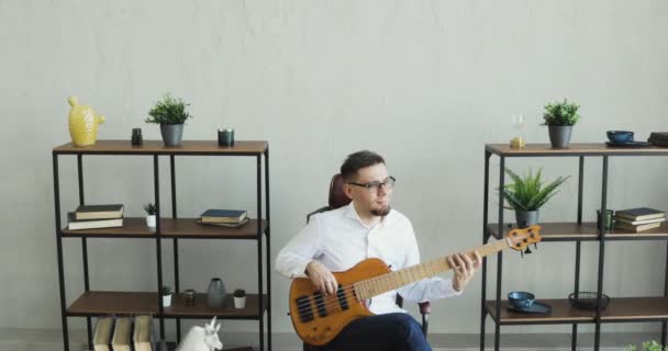 Office worker is playing on guitar and enjoying it sitting at work during break. — Stock Video