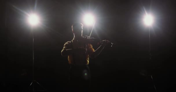 Man professional violinist plays violin in light of spotlights, front view. — Stock Video