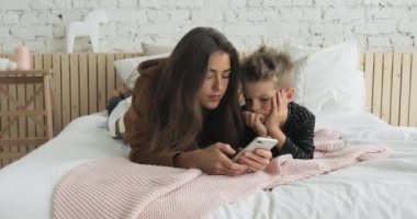 Anne ve oğlu akıllı telefonları karıştırıyor çocuk odasında yatakta yatıyor, çok sıkıcı..