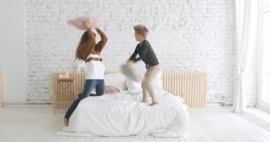 Mutlu aile anne ve oğlu, çocuk odasındaki yatakta yastık kavgası yapıyor..