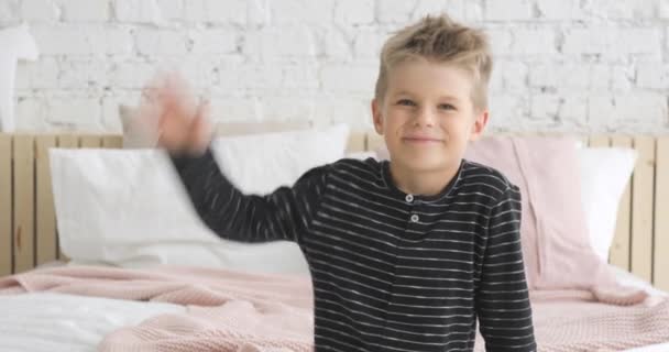 Portrait de petit garçon souriant de 5 ans regardant la caméra et agitant la main . — Video