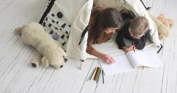 Famille maman et fils dessin crayons ensemble couché dans tipi dans la pépinière, vue du dessus . — Video