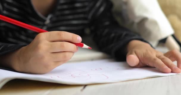 Menino criança pequena está pintando imagem usando lápis vermelho no álbum, mãos close-up . — Vídeo de Stock