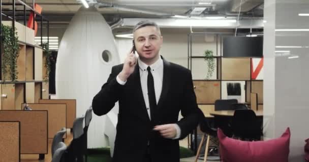 Retrato de hombre de negocios caminando teléfono inteligente hablando trabajando en la oficina moderna . — Vídeo de stock